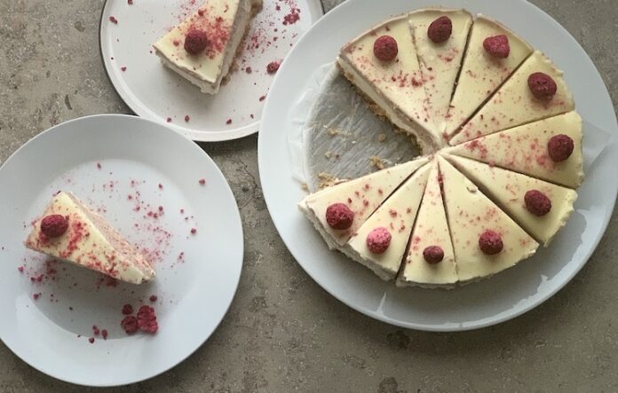 Nepečený čokoládový cheesecake, dozdobený malinami a bielou Ganache.