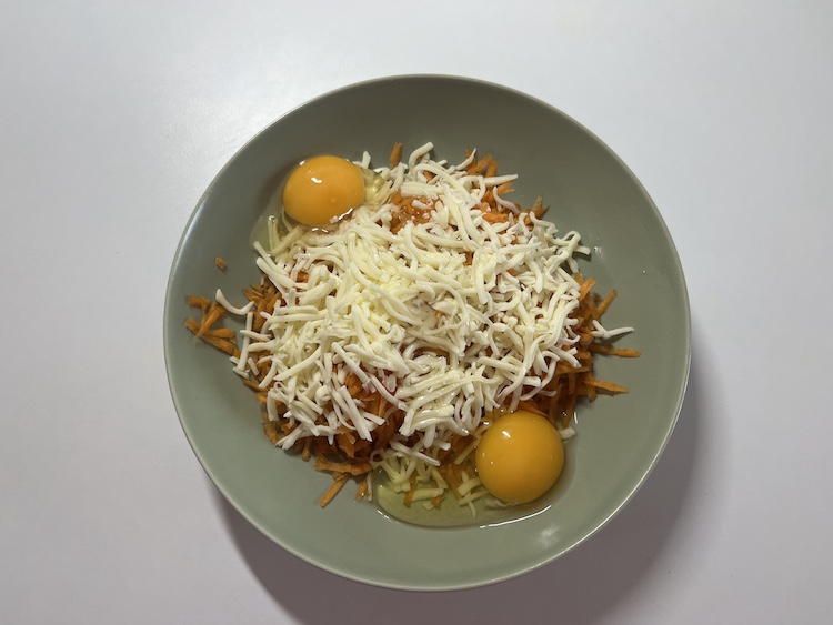 2. K nastrúhaným mrkvám následne pridáme strúhaný syr. My sme si vybrali mozzarellu, avšak môžeme zvážiť akýkoľvek iný druh podľa vlastnej preferencie. Pridáme aj dve vajíčka a všetko spolu rukami zmiešame do jednotnej zmesi. Fotka - Zuzana Zsilleová