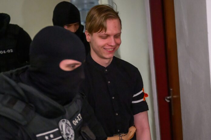 Samuel S. prichádza v sprievode eskorty do pojednávacej miestnosti na Špecializovanom trestnom súde v Pezinku (13. 4. 2026.) Foto TASR - Jaroslav Novák